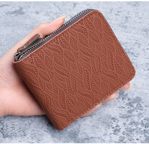 Detailed view of a brown leather wallet featuring leaf-vein embossed texture and a U-shaped zipper