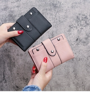 Detail of pink and black trifold wallets with lychee texture and rivet snap closures