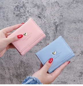 Detail of mini tri-fold wallets in pastel pink and blue with gold heart buckle