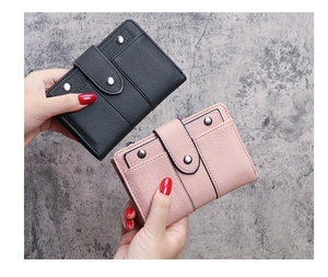 Detail view of pink and black leather wallets featuring vintage rivets and buckle closure