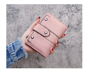 Close-up of pink frosted leather wallet with rivet studs and cross stitching details