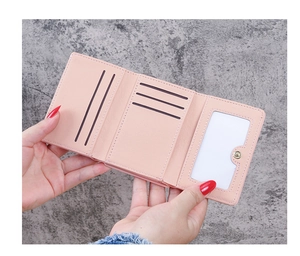 Detail of pink faux leather tri-fold wallet showing card slots and ID window
