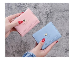 Close-up of small pink and blue leather wallets featuring a gold heart clasp