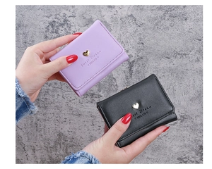 Close-up of purple and black trifold wallets featuring golden heart metal accents
