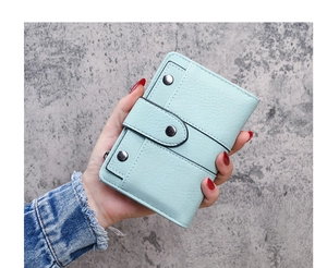 Detail of mint green tri-fold wallet with lychee texture leather and metal rivets
