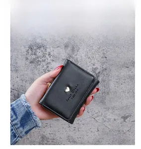 Close-up of black lychee leather mini wallet featuring golden heart and Sweet Dream text