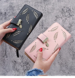 Detail of hollow leaf pattern and metal pendant on long leather wallets in pink and black