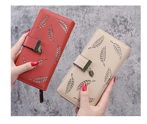 Close-up of hollow leaf pattern and metal pendants on red and beige long wallets