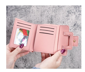 Detail view of pink trifold wallet showing five card slots and a clear ID window