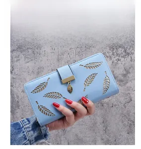 Detailed view of hollow leaf pattern and gold metal pendant on a light blue wallet