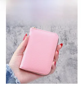 Close-up of pink litchi grain leather card holder with gold zipper and neat stitching