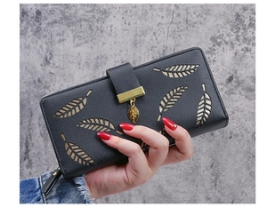 Detail of black long leather wallet featuring hollow leaf design and gold leaf pendant charm