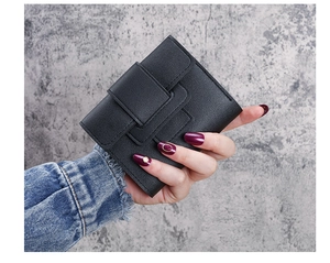 Close-up of a compact black pebble grain leather wallet held by hand for scale
