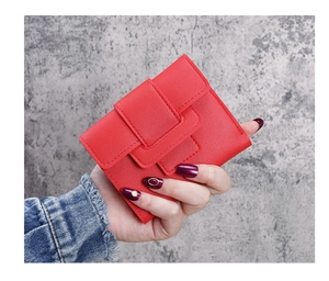Detailed view of red tri-fold leather wallet with tiered buckle held in hand