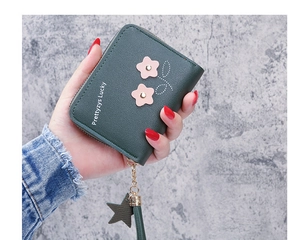 Macro shot of a dark green pebble leather zip wallet with pink flower charm detail