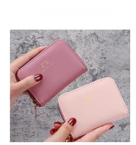 Close-up of pink leather accordion card holders with gold cat logo and metal zipper