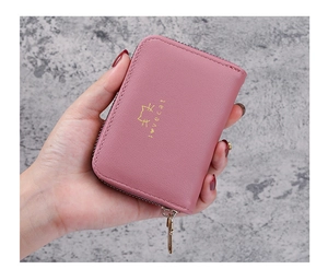 Close-up of pink leather wallet with gold Love Cat text held in hand on gray background