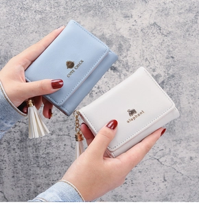 Close-up of light blue and beige trifold wallets with tassels and animal prints