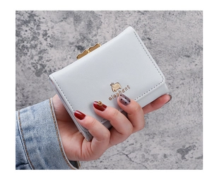 Detail of short leather wallet with golden elephant buckle and precise white stitching
