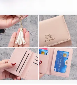 Detail view of the pink faux leather wallet featuring a cat motif and tassel charm accessory