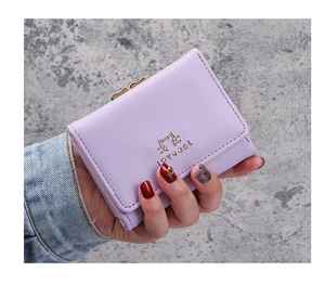 Close-up of small purple tri-fold wallet with cat-ear gold clasp held by a model