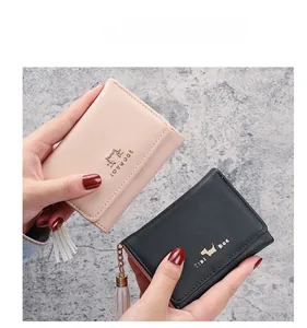 Detailed view of women's short tri-fold wallets in pink and black with fringe tassel