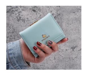 Close-up of mint blue trifold short wallet with gold elephant emblem and metal clasp