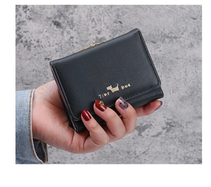 Detail of black tri-fold wallet featuring pebble leather and golden dog emblem clasp