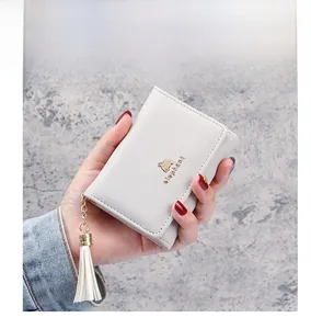 Detailed macro shot of a cream tri-fold wallet with a gold elephant logo and tassel