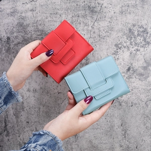 Chic trifold mini purses in red and light blue colors held in hand against a grey background