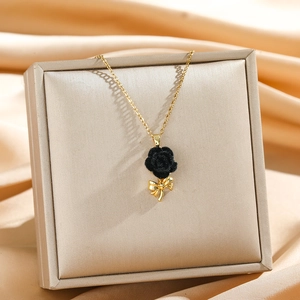 Elegant gold necklace with a black velvet rose pendant and bow on a display stand
