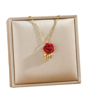 Elegant gold necklace featuring a red rose pendant with a delicate bowknot detail