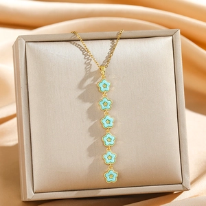 Long collier pampille fleurs émail bleu et chaîne dorée sur fond satiné élégant