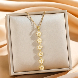 Collier à pampilles dorées avec six fleurs en émail blanc sur une boîte à bijoux en soie