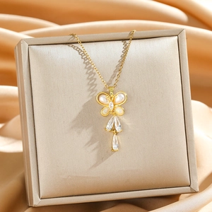 Elegant gold butterfly necklace with pearl wings and crystal drops on a gift box