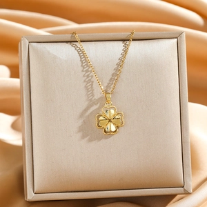Golden clover pendant necklace made of titanium steel displayed on silk fabric background