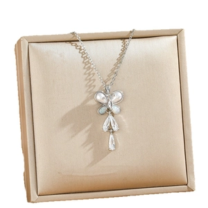 Silver butterfly necklace with pearl wings and teardrop crystal on a golden jewelry pad