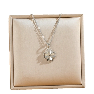 Silver four-leaf clover pendant necklace with granular texture in a luxury gift box