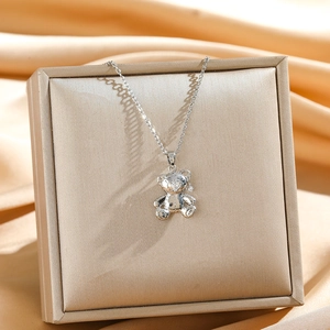 Elegant silver teddy bear pendant necklace with sparkling stones on a gold jewelry box