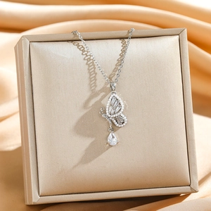 Collier papillon élégant avec zircone et pendentif goutte sur fond de soie luxueuse