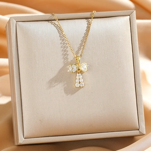 Elegant gold bow necklace with white cubic zirconia pavé on premium silk background