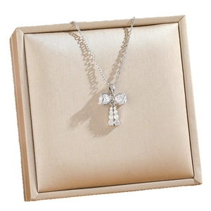 Elegant bow pendant necklace with heart-shaped crystals on champagne velvet jewelry box