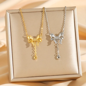 Elegante Halskette mit Schleifen- und Herzanhänger in Gold und Silber auf Seide