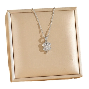 Collier trèfle à quatre feuilles argenté serti de cristaux sur un présentoir métallique