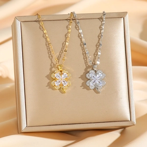 Elegant gold and silver four-leaf clover crystal necklaces on luxury jewelry box