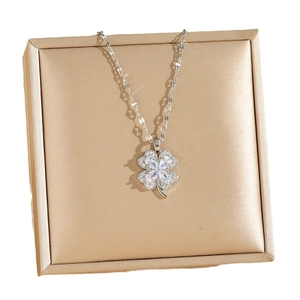 Elegant silver four-leaf clover necklace with sparkling cubic zirconia on a jewelry box