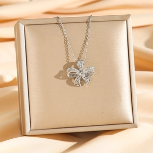 Eleganter Hohlfiligran-Schleifenanhänger in Silberoptik über einer luxuriösen Geschenkbox