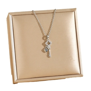 Sparkling key necklace with heart charms in silver stainless steel on a luxury jewelry box