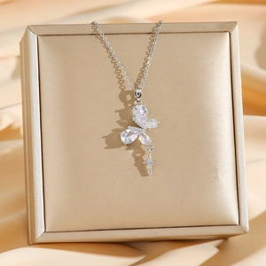 Collier papillon en titane avec pendentif croix sur un fond de soie élégant et chic