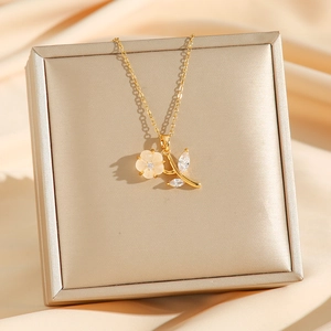 Elegant gold flower necklace with pink petals and zircon leaves on jewelry box